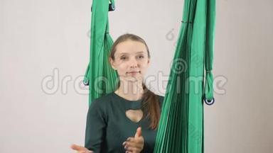 年轻的女人坐在吊床上展示<strong>过来</strong>，<strong>过来</strong>给我签名。 空中航空飞行健身教练训练。 冥想